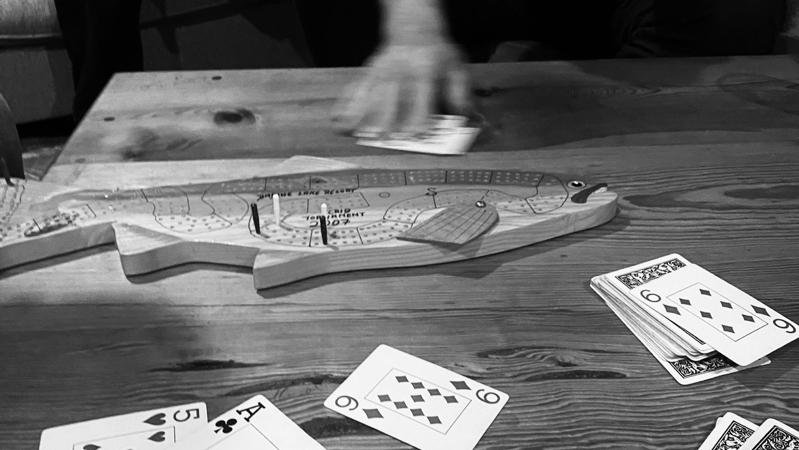 A rainbow trout shaped cribbage board in use by a family.