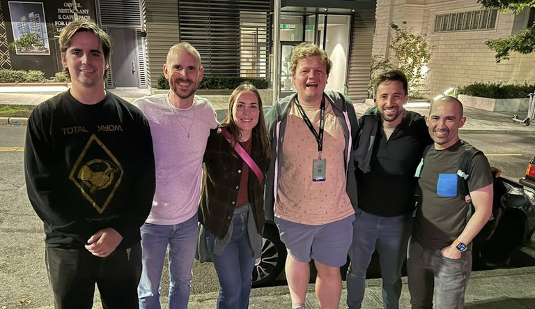 Several people in a line with arms around each other outside of a pizza joint in Seattle